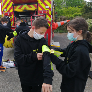 Les élèves s'entraident à mettre leur tout nouveau brassart reçu des mains du Capitaine